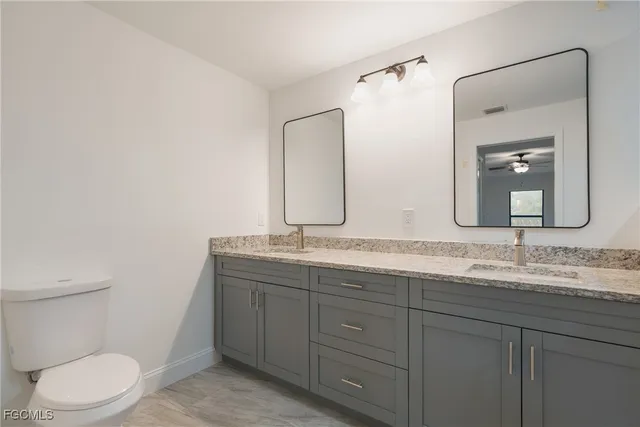 a bathroom with a granite countertop toilet sink and mirror