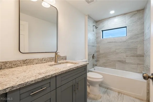 a bathroom with a granite countertop sink a toilet and bathtub