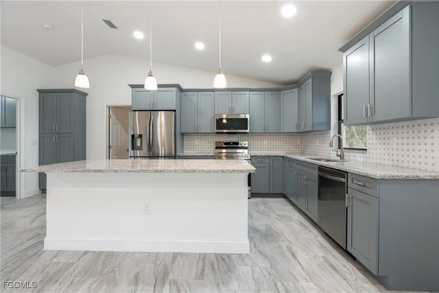 a large kitchen with stainless steel appliances kitchen island a large counter top and a stove top oven