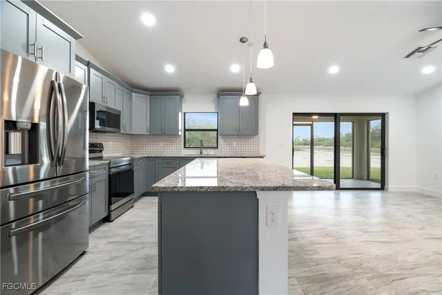 a kitchen with stainless steel appliances granite countertop a refrigerator and a stove top oven