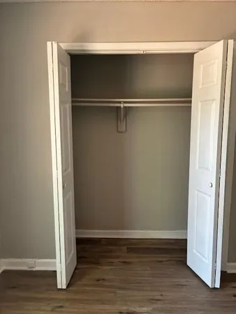 a view of an empty walk in closet with wooden floor