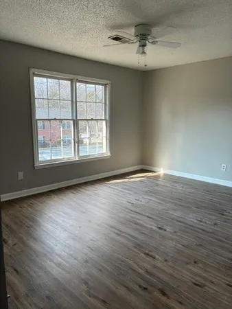 an empty room with wooden floor and windows