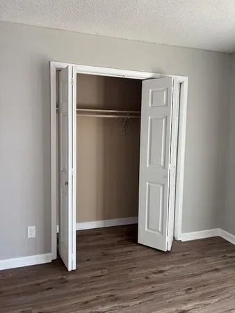 a view of an empty room with wooden floor and closet