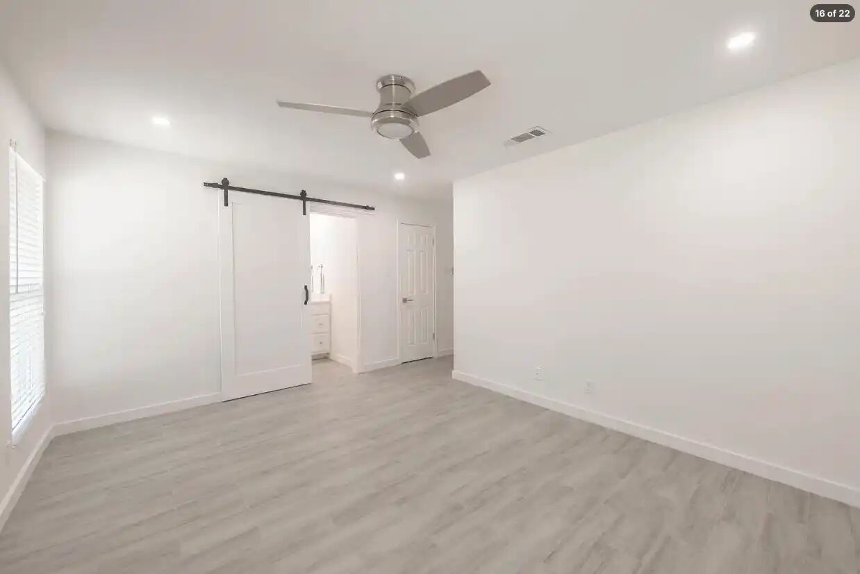 303 Fantail Loop, Unit B Austin, TX 78734 - Photo 7 of 11 Sleek wood-style floors and a sliding barn door elevate this modern bedroom.