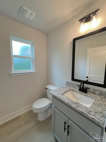 a bathroom with a granite countertop toilet a sink and a mirror