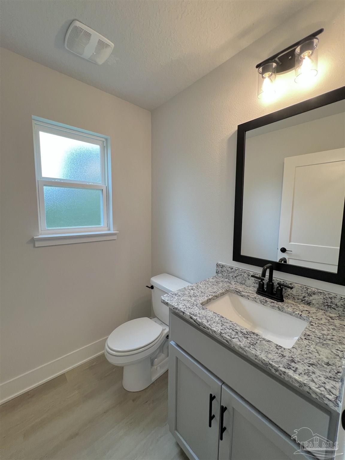 944 Rustling Pnes Road, Unit 12B Cantonment, FL 32533 - Photo 7 of 16 a bathroom with a granite countertop toilet a sink and a mirror