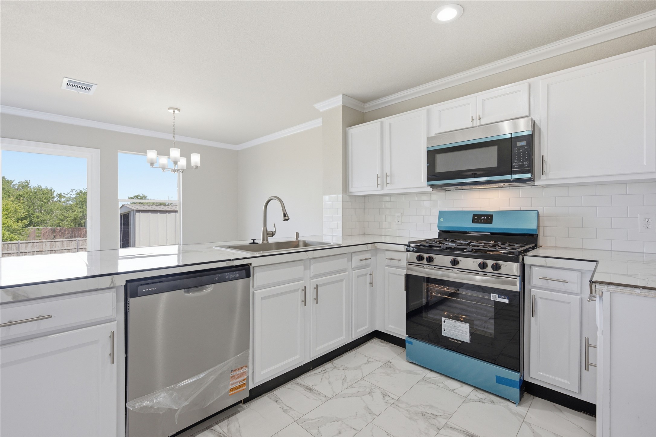 6917 Panda Royle Drive Del Valle, TX 78617 - Photo 9 of 23 A well-appointed kitchen features stainless steel appliances, crisp white cabinetry, and modern marble-look flooring.