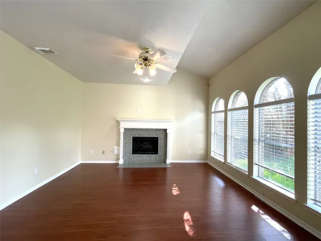 a view of empty room with wooden floor and fan