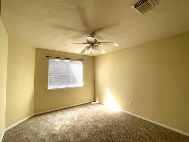 an empty room with a chandelier fan and windows