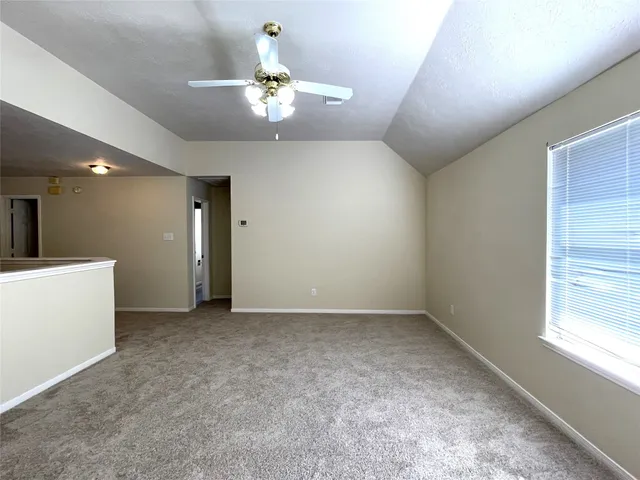 an empty room with a chandelier fan and windows