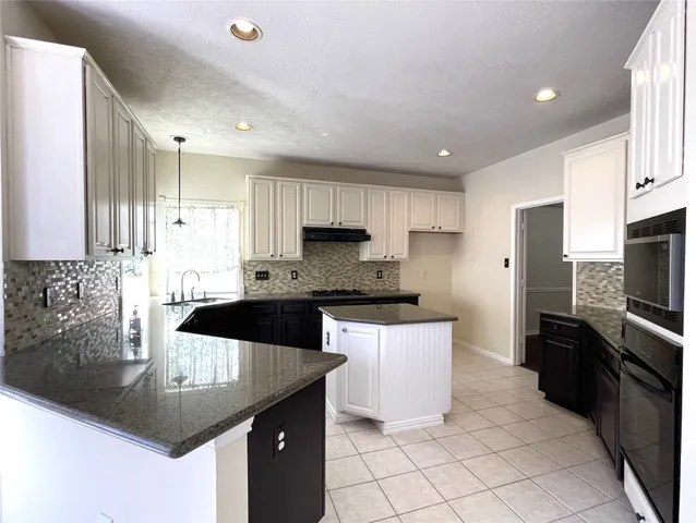 a kitchen with granite countertop a sink a counter top space appliances and cabinets