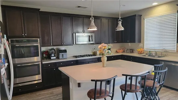 a kitchen with stainless steel appliances granite countertop a kitchen island a table and chairs in it