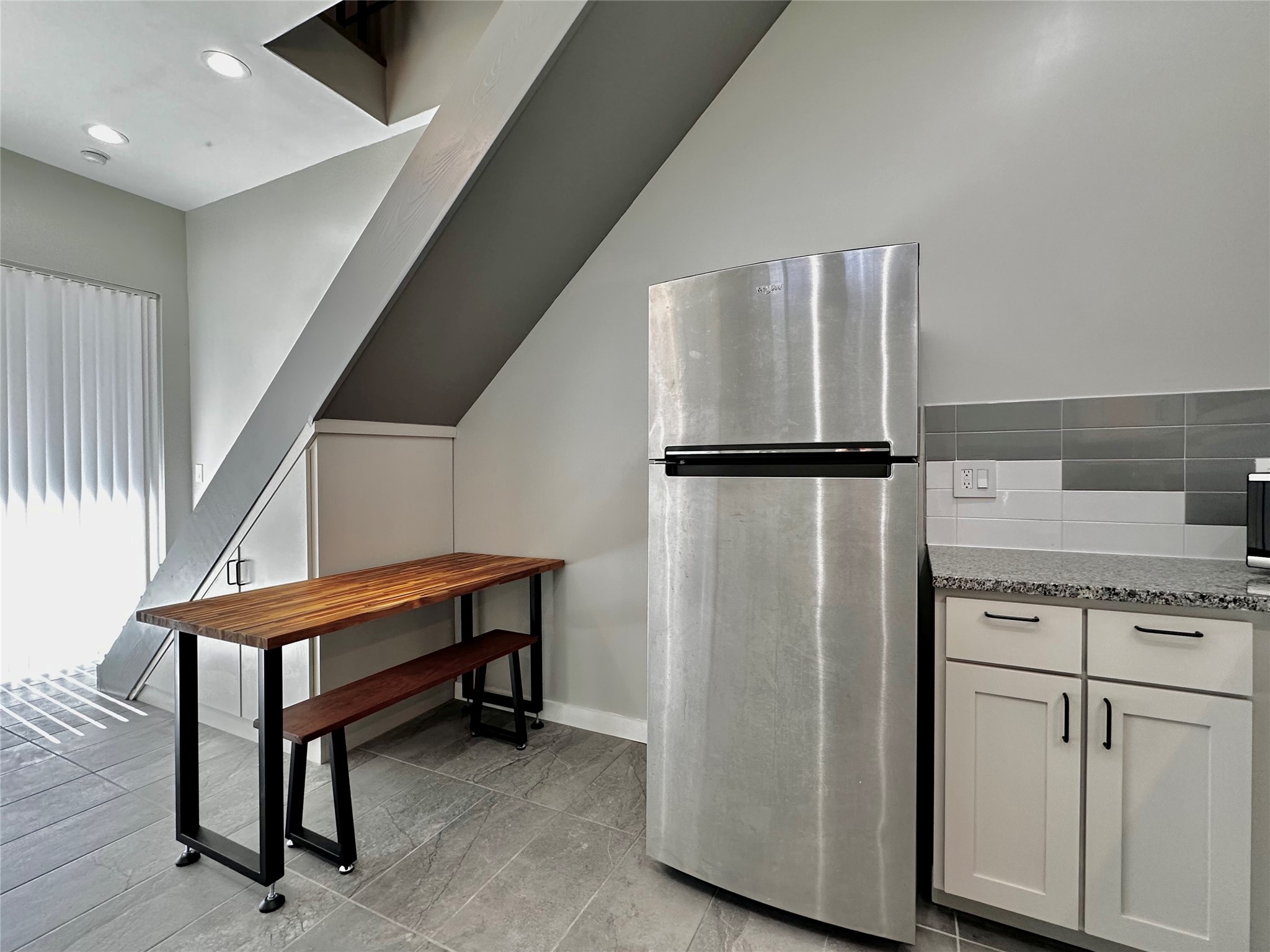 914 East 39th Street, Unit 2 Austin, TX 78751 - Photo 12 of 34 Seating with freestanding refrigerator, light stone countertops, and white cabinetry