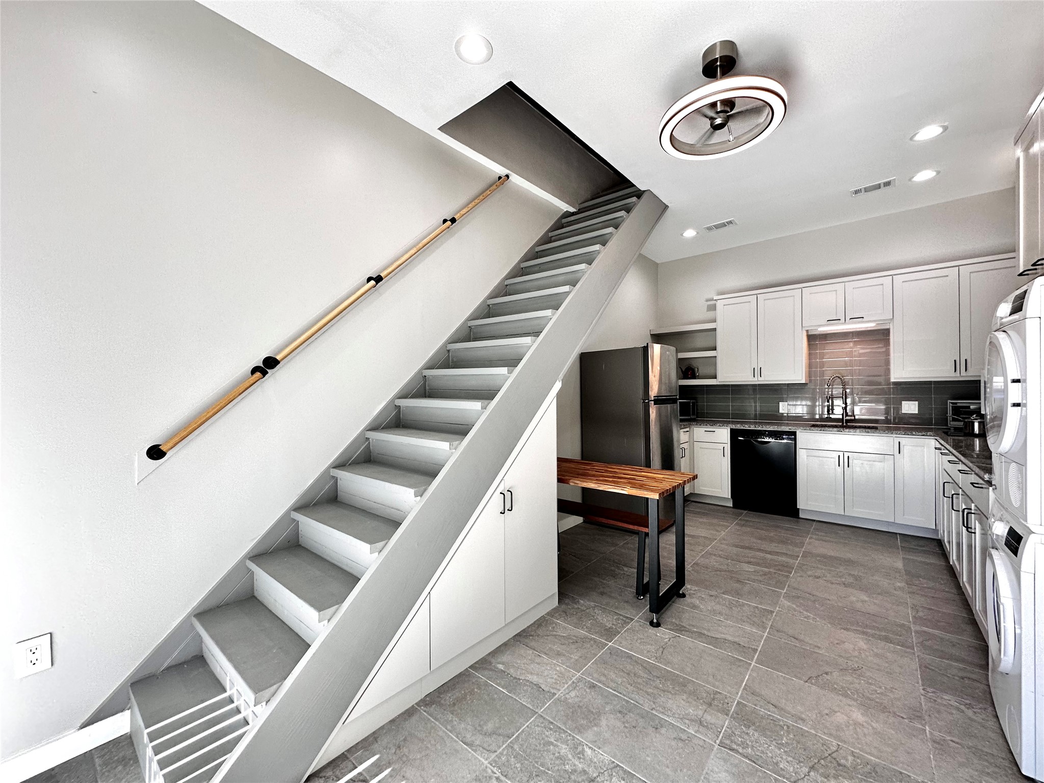914 East 39th Street, Unit 2 Austin, TX 78751 - Photo 5 of 34 Modern kitchen area featuring white cabinetry, stainless steel appliances, and a dark tile backsplash