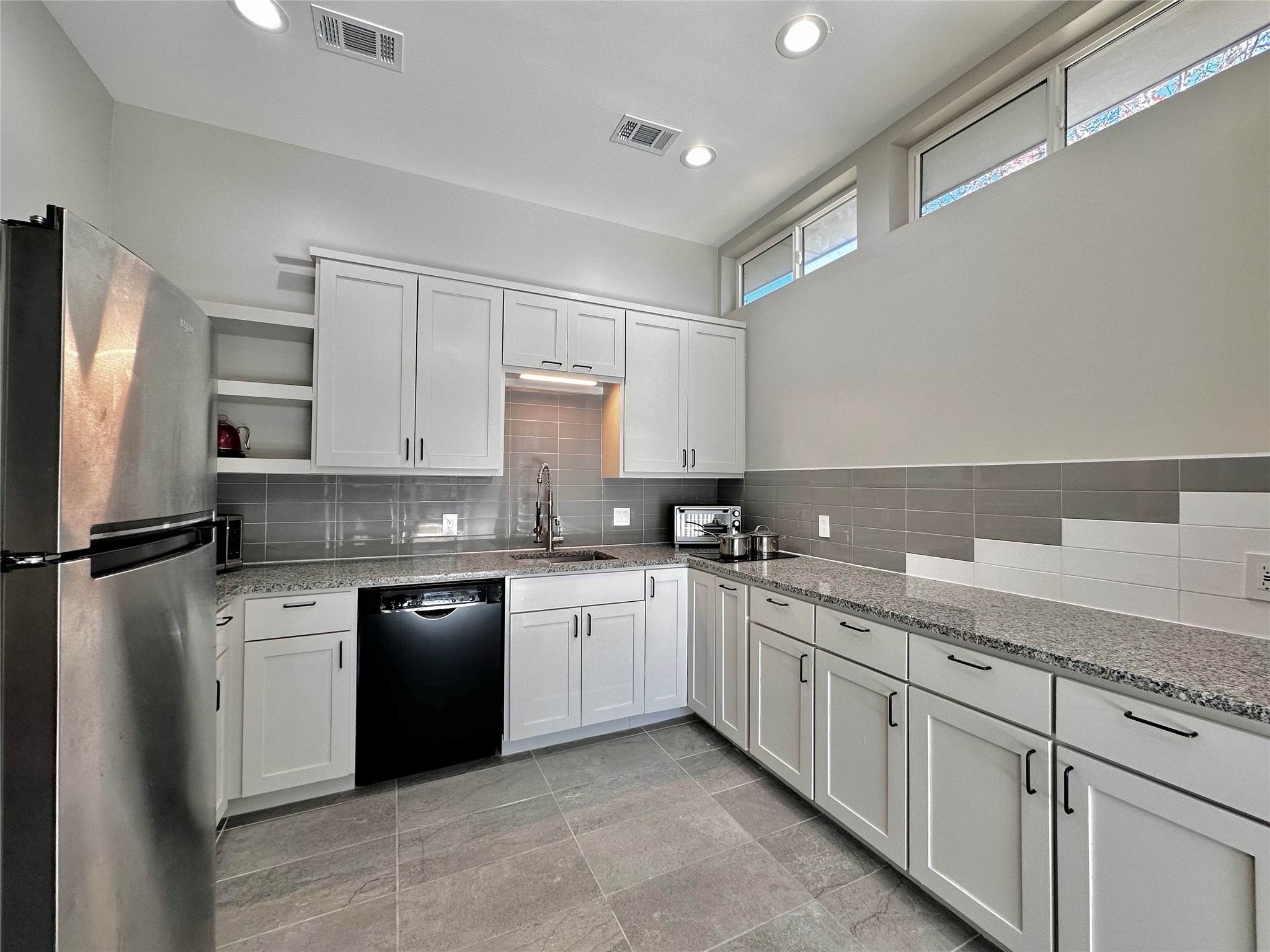 914 East 39th Street, Unit 2 Austin, TX 78751 - Photo 9 of 34 Kitchen featuring freestanding refrigerator, white cabinetry, light stone counters, and recessed lighting