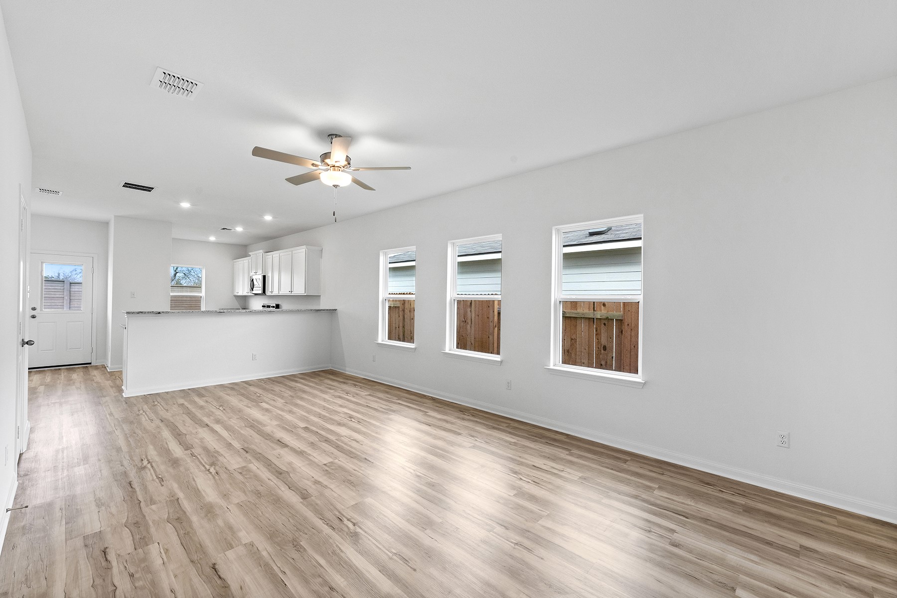 14408 Wahlbergs Way Elgin, TX 78621 - Photo 2 of 14 a view of an empty room with a kitchen and wooden floor