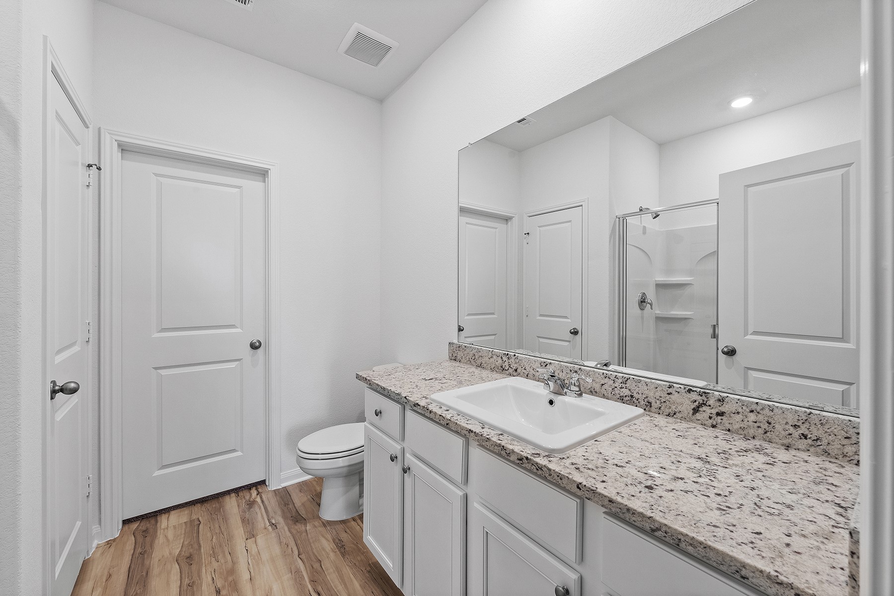 14408 Wahlbergs Way Elgin, TX 78621 - Photo 9 of 14 a bathroom with a granite countertop sink a toilet and a large mirror