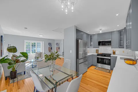 a living room with stainless steel appliances furniture a dining table and kitchen view