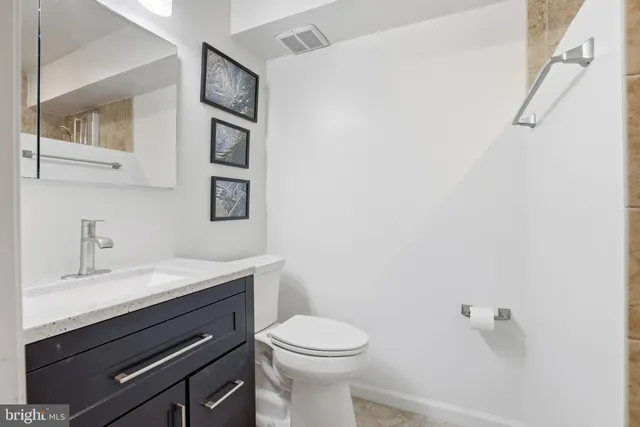 a bathroom with a toilet sink vanity and mirror