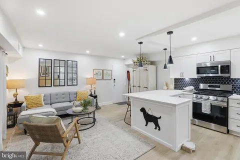 a living room with stainless steel appliances kitchen island a table and chairs in it
