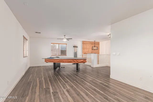 an empty room with wooden floor and a ceiling fan