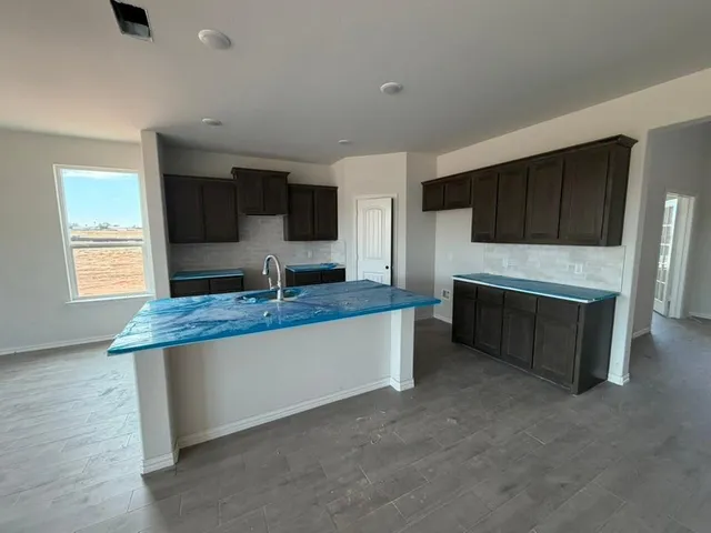 a living room with stainless steel appliances kitchen island granite countertop a stove and a sink