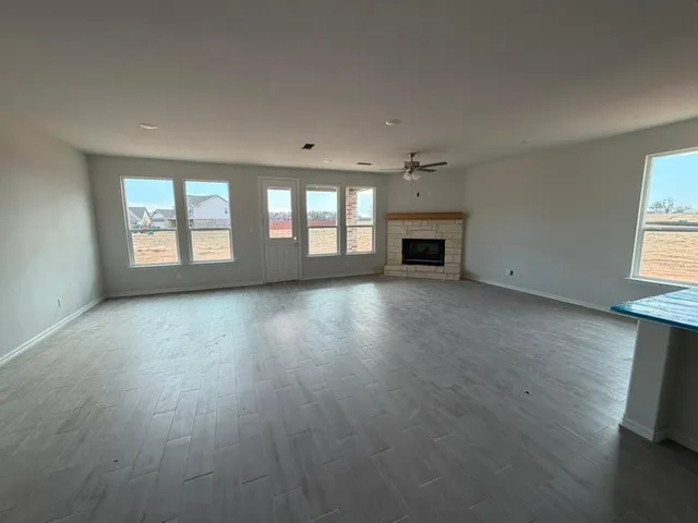 an empty room with wooden floor fireplace and windows