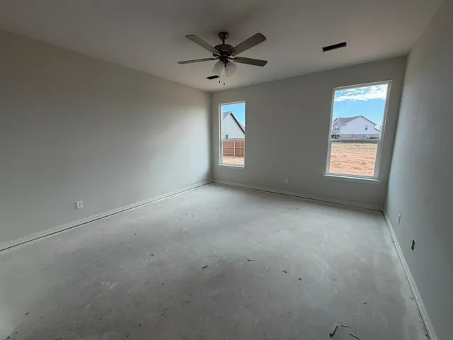 an empty room with windows and ceiling fan