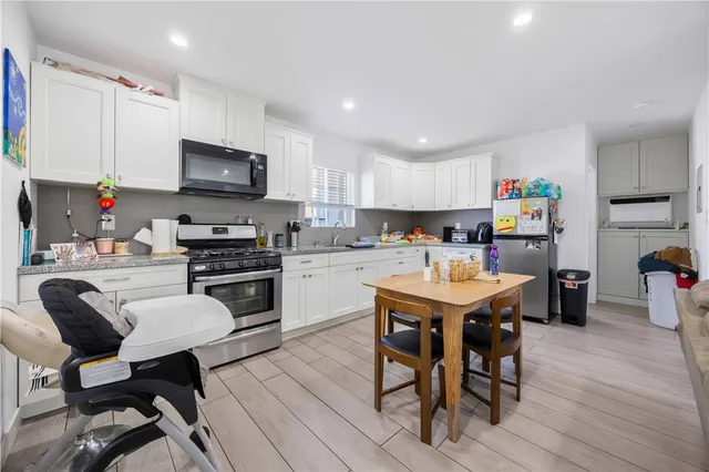 a kitchen with a dining table chairs refrigerator and microwave