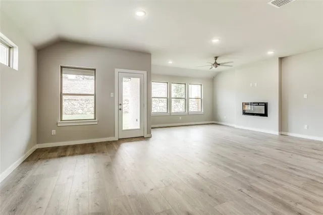 a view of an empty room with a window and wooden floor
