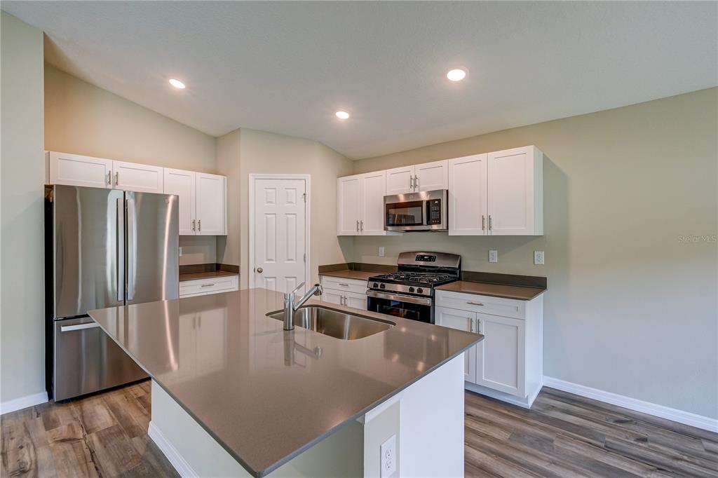 12730 Hysmith Loop Parrish, FL 34219 - Photo 8 of 33 a kitchen with stainless steel appliances granite countertop a sink a stove a refrigerator a washer dryer and white cabinets