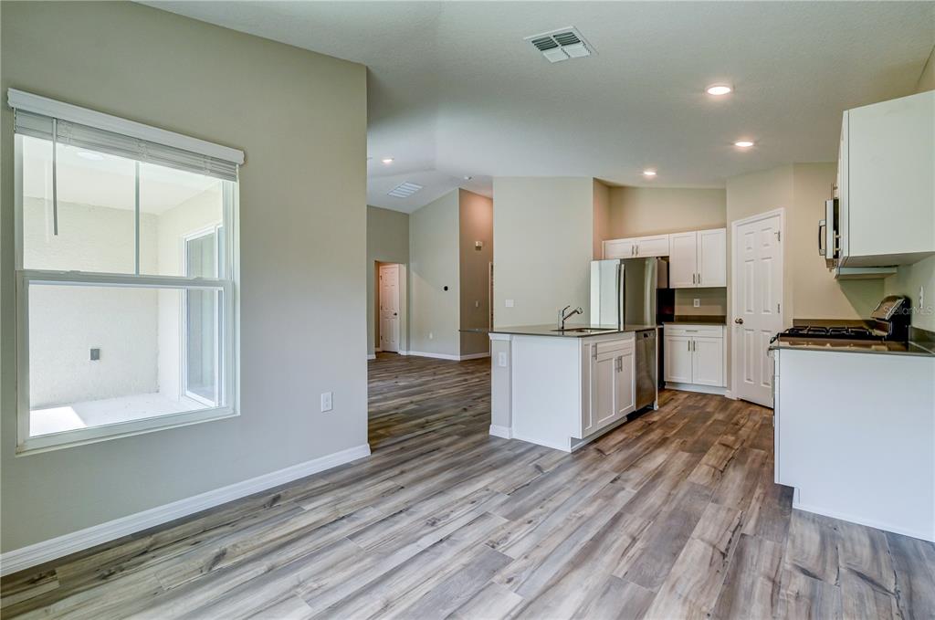 12730 Hysmith Loop Parrish, FL 34219 - Photo 10 of 33 a kitchen with stainless steel appliances kitchen island wooden floors and white cabinets