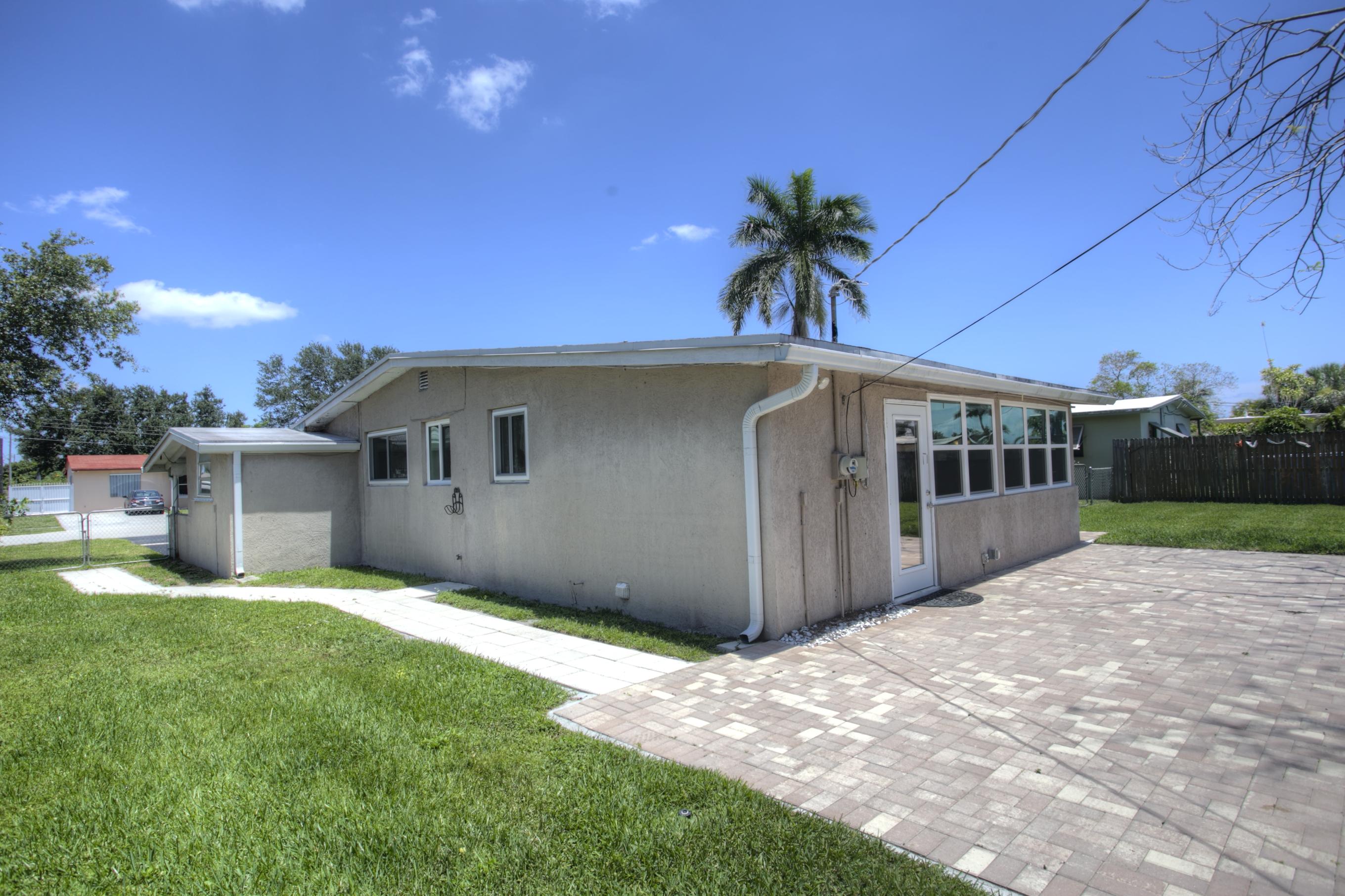 353 Shady Lane Road Palm Springs, FL 33461 - Photo 19 of 30 a front view of a house with a yard and garage