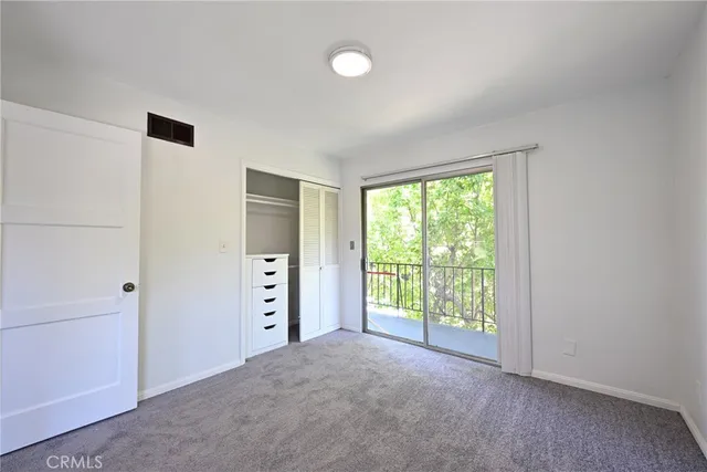 a view of an empty room with a window and a kitchen