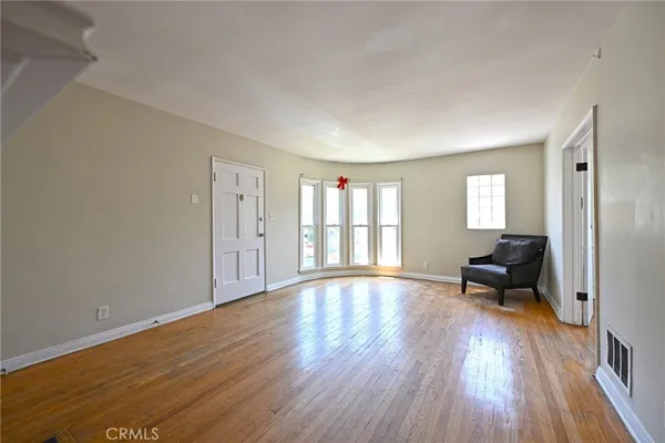 a view of empty room with wooden floor and a window
