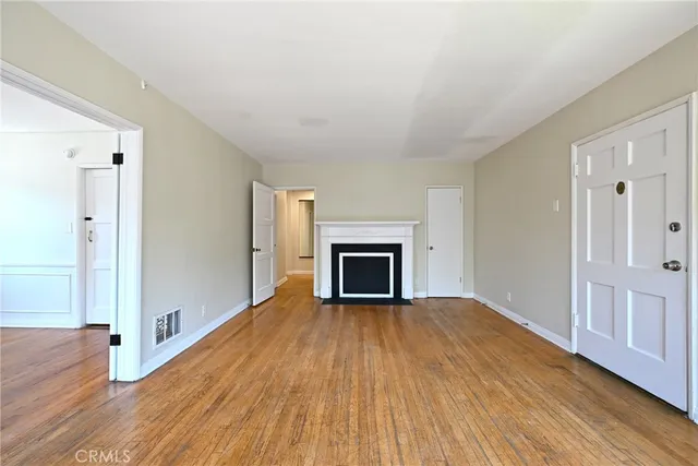 a view of a livingroom with wooden floor and a fireplace