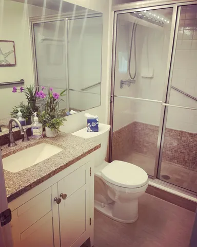 a bathroom with a granite countertop sink toilet and shower