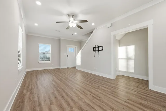 a view of an empty room with wooden floor and a window