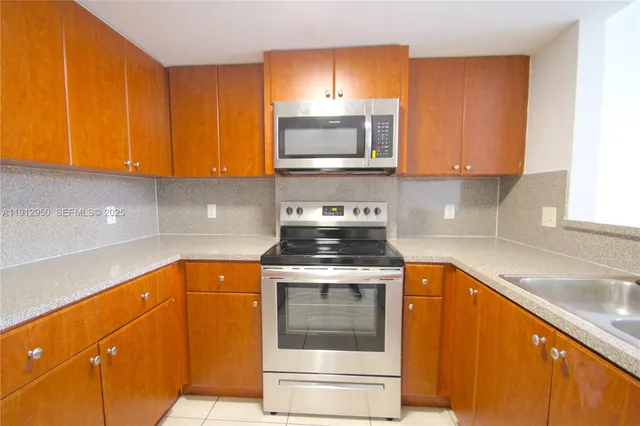 a kitchen with granite countertop a stove top oven microwave and cabinets