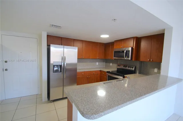 a kitchen with stainless steel appliances granite countertop a refrigerator a sink a stove and cabinets