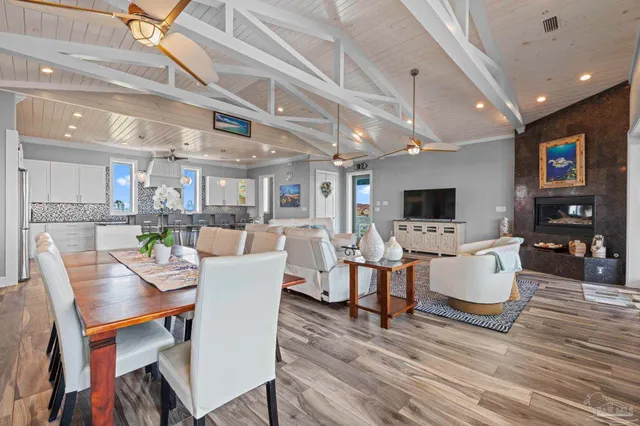 a kitchen with stainless steel appliances granite countertop a stove top oven a sink a dining table and chairs with wooden floor