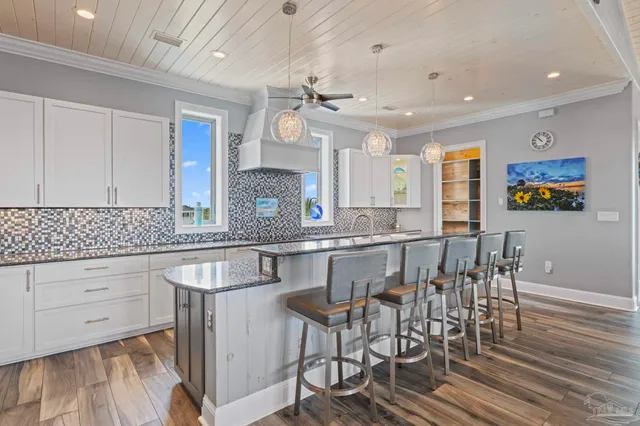 a kitchen with stainless steel appliances granite countertop a sink a stove a refrigerator and island with wooden floor