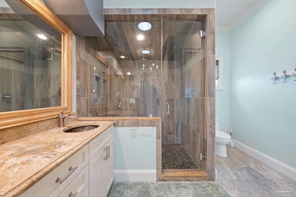 a bathroom with a granite countertop sink a mirror and shower