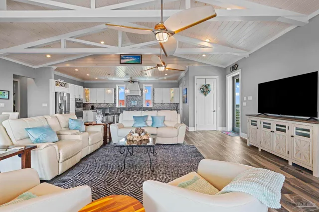 a living room with furniture kitchen view and a flat screen tv