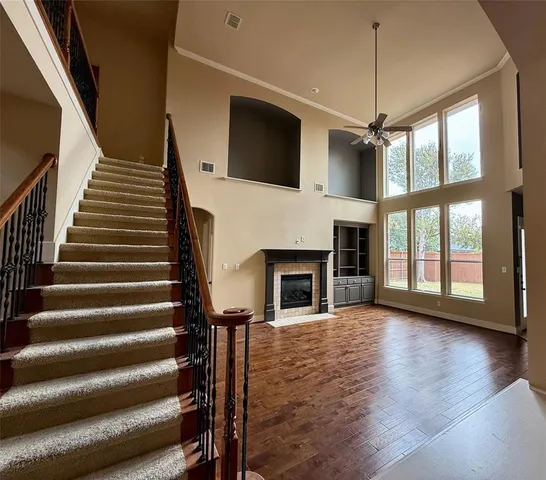 a view of a livingroom with wooden floor staircase fireplace and windows
