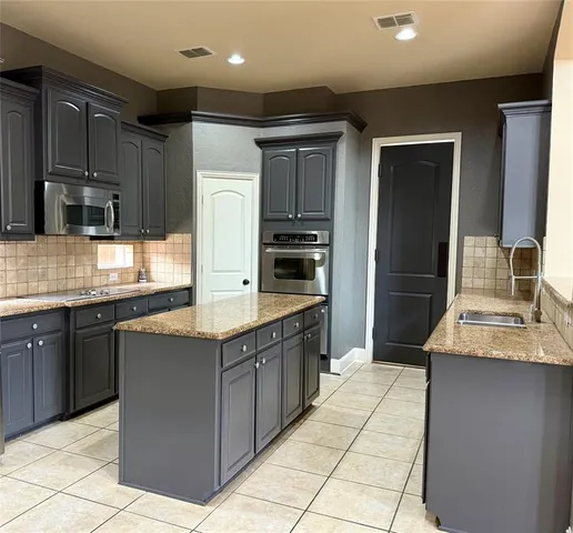 a kitchen with stainless steel appliances granite countertop a refrigerator and a stove top oven