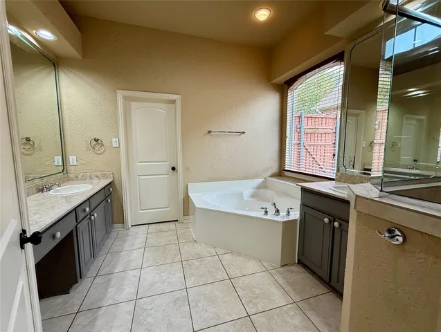 a spacious bathroom with a granite countertop sink a mirror and a bathtub