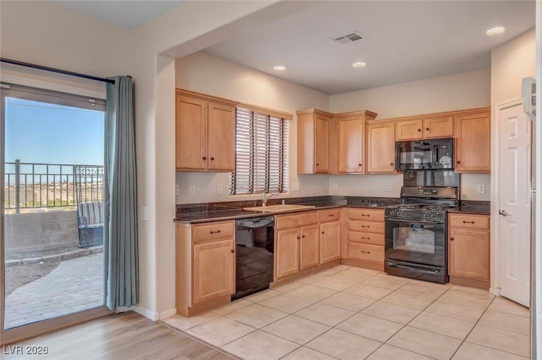 2460 Rue Bienville Way Henderson, NV 89044 - Photo 14 of 50 Kitchen featuring black appliances, light brown cabinets, dark stone counters, light tile patterned flooring, and recessed lighting