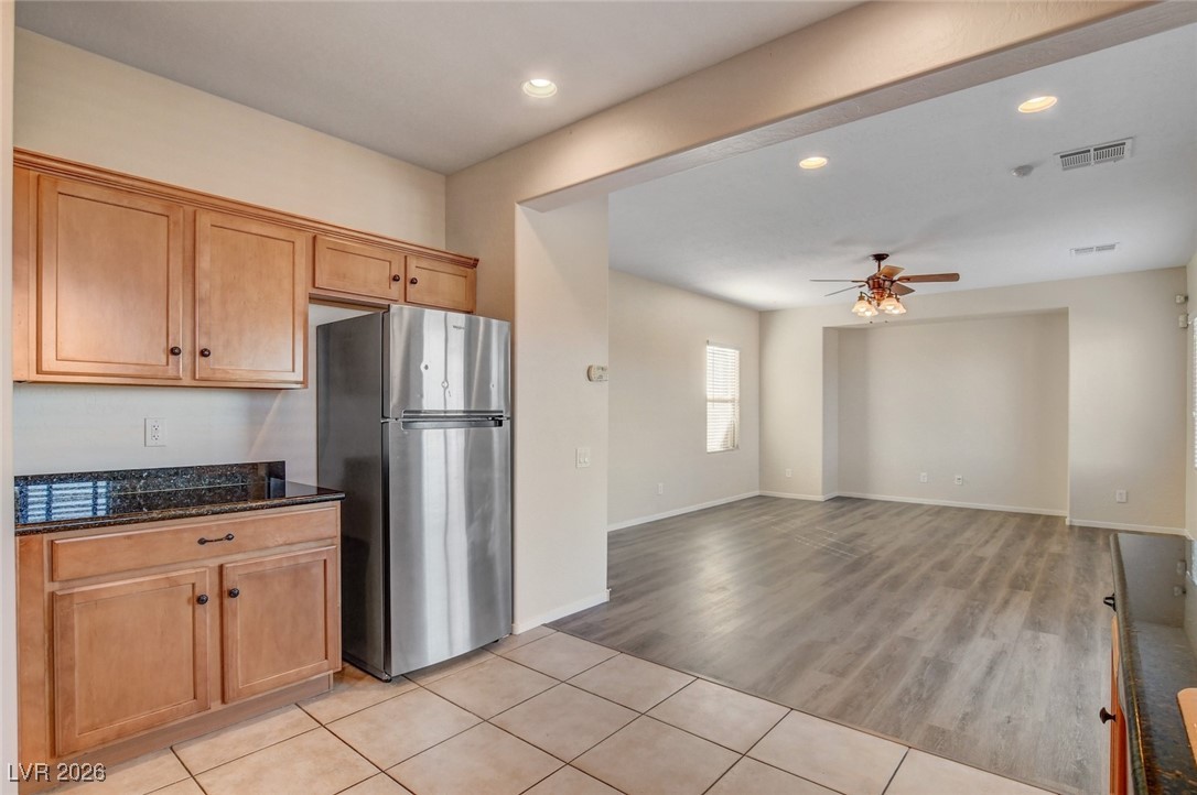 2460 Rue Bienville Way Henderson, NV 89044 - Photo 15 of 50 Kitchen featuring freestanding refrigerator, recessed lighting, dark stone countertops, light tile patterned flooring, and ceiling fan
