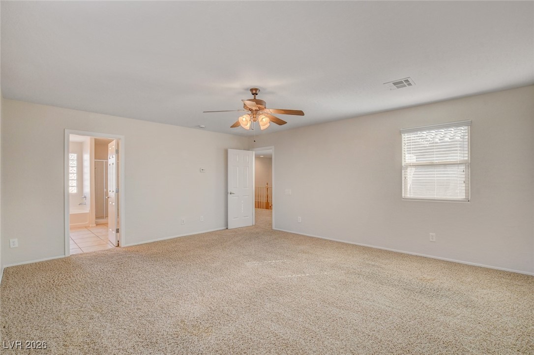 2460 Rue Bienville Way Henderson, NV 89044 - Photo 31 of 50 Unfurnished bedroom featuring light carpet, ceiling fan, and ensuite bath